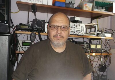 Ralf Meeh an seiner Funkstation, im Hintergrund Regale mit Funkgeräten und Messtechnik